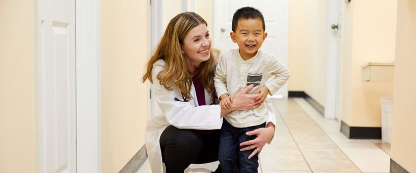 A doctor kneeling down smiling with a patient.
