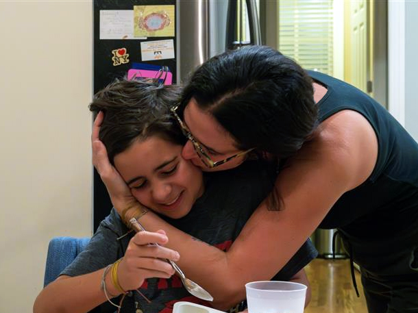 A mother gives her son a kiss on the cheek.